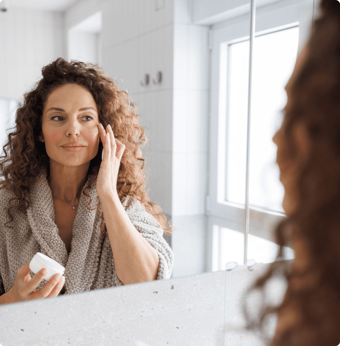 Woman with curly hair applying face cream