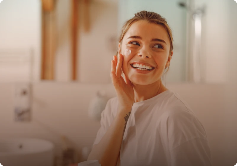 Smiling woman using face cream